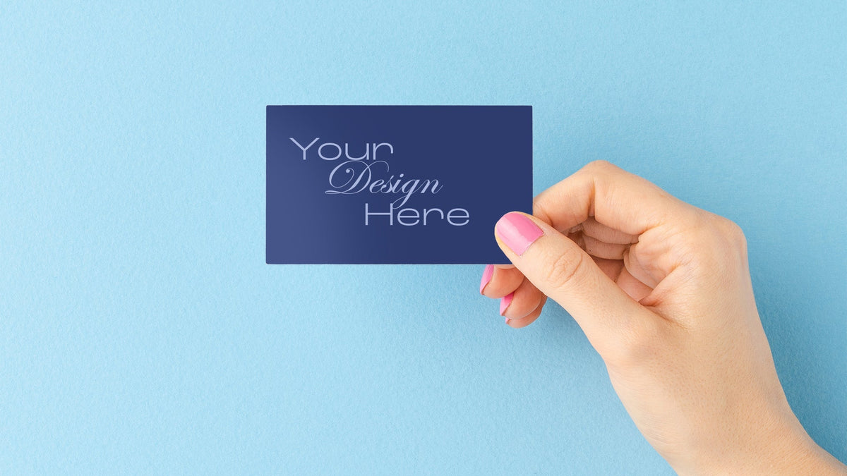 Hand holding a blue card with 'Your Design Here' text on a light blue background